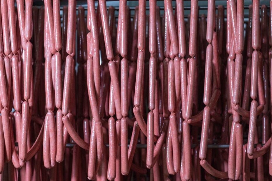 Rows of sausages hanging in a cold storage room for meat processing.